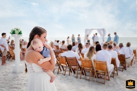 On the beach of Anna Maria Island, FL, a family member gently quiets the baby during the wedding ceremony.